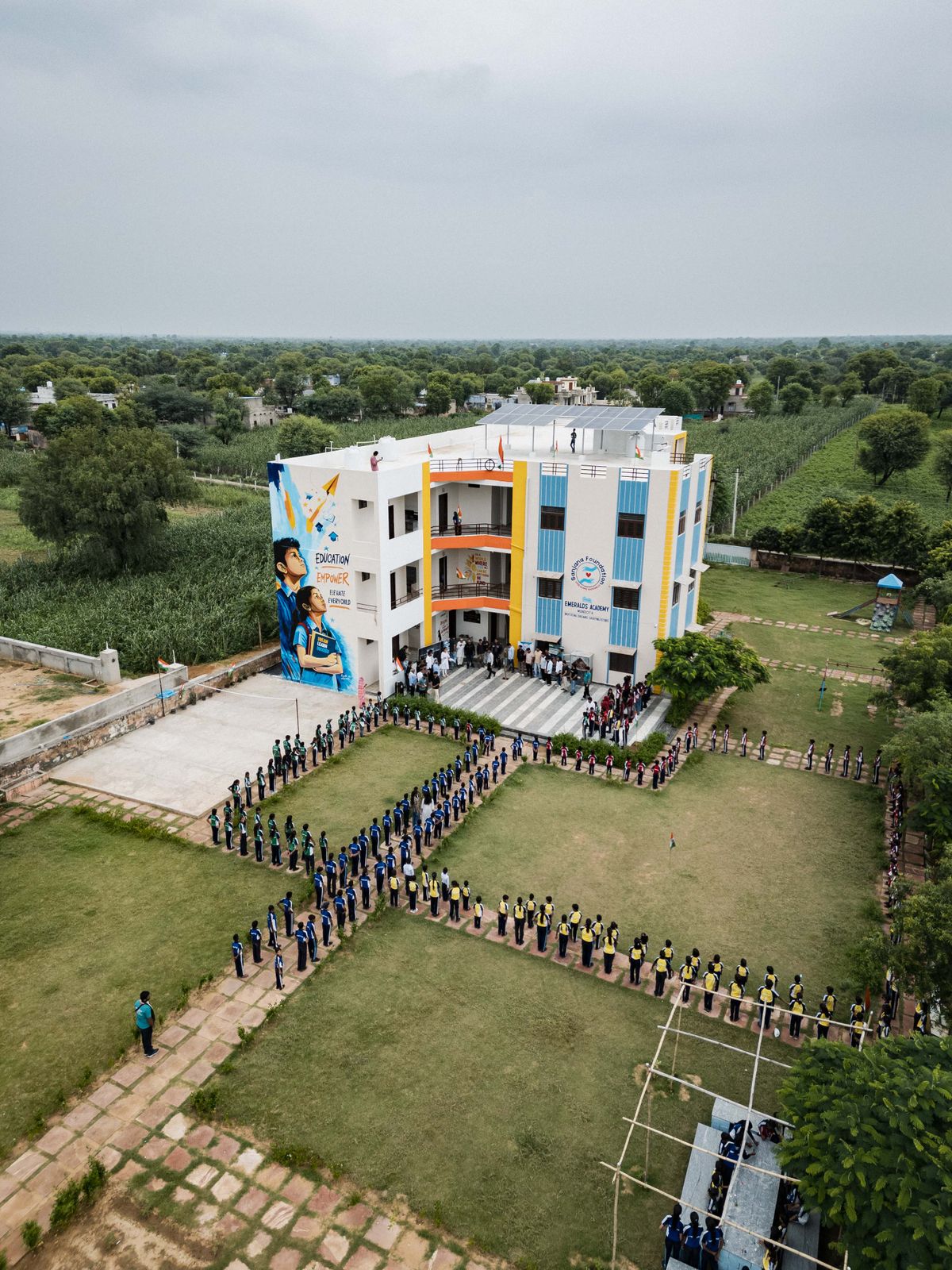 Aerial view of a school building and morning assembly on the lawns