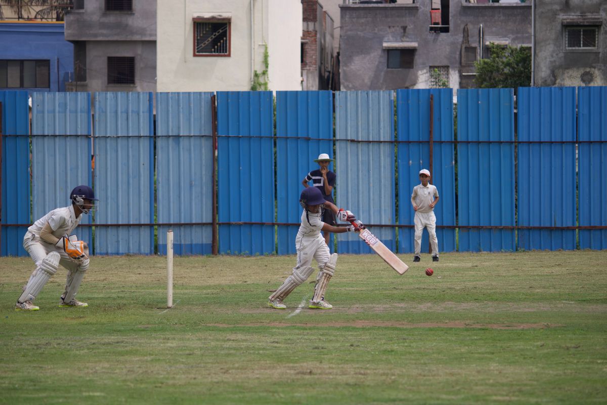 Students playing a cricket match on the ground