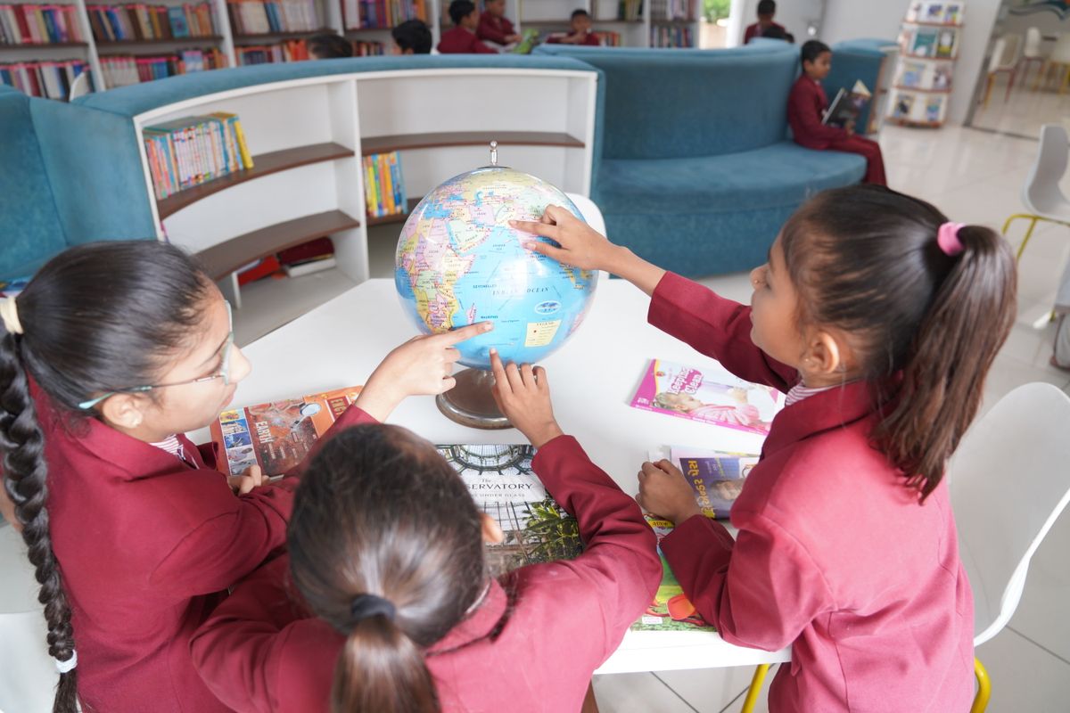 Students exploring a globe in the library