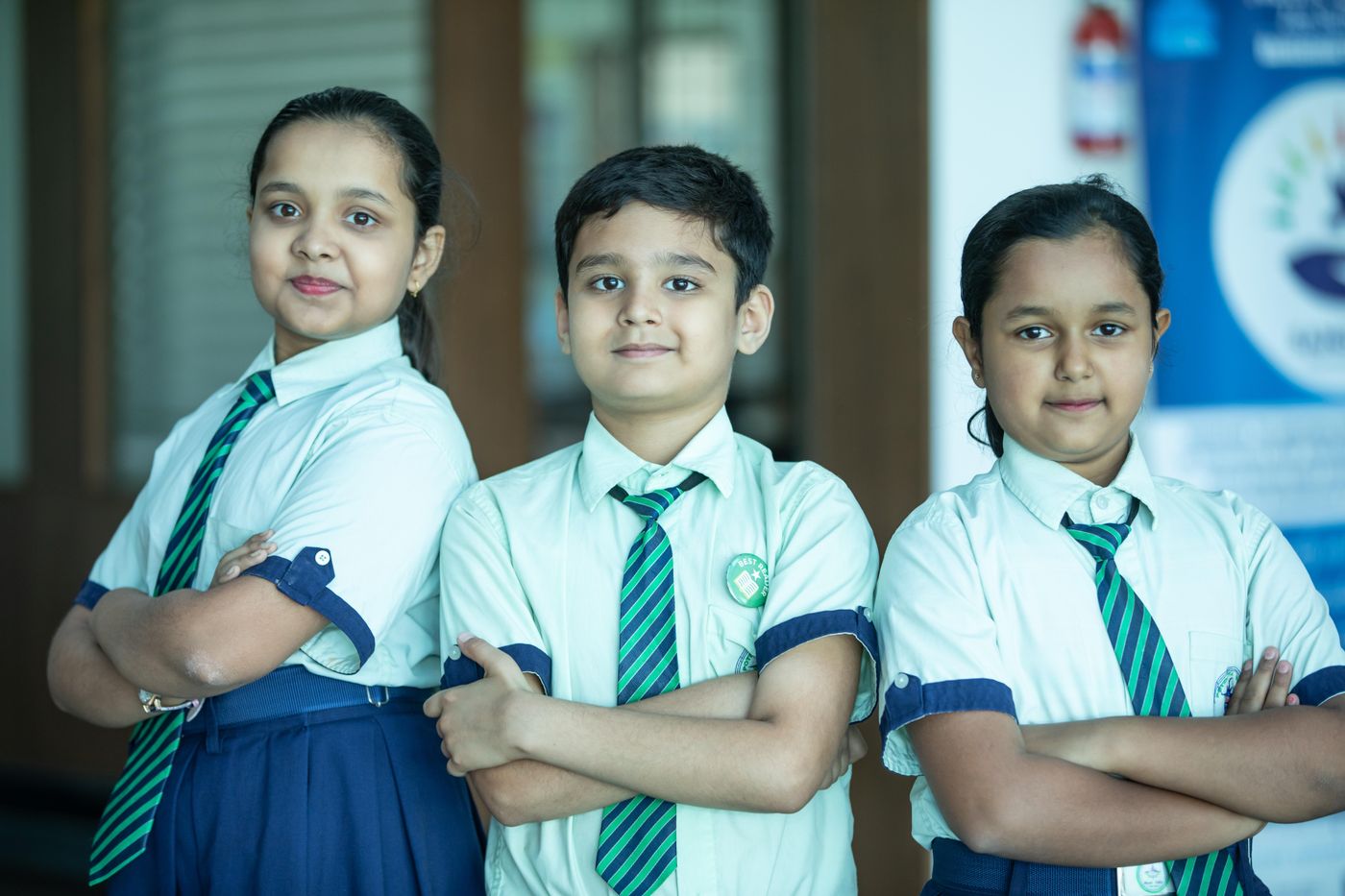 Three students in school uniform standing with arms folded